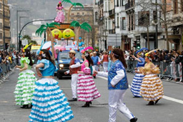 Santa Barbara konpartsa Donostiako kaleetan zehar desfilatzen, hondoko karrozarekin