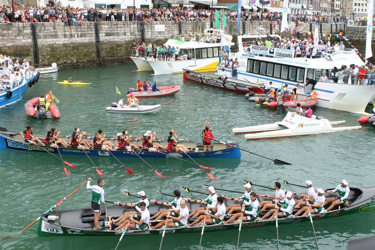 Trainera femenina de Zumaia junto a la trainera masculina de Kaiku en el puerto.