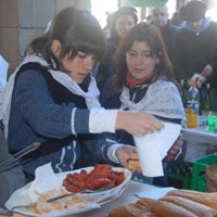 Dos chicas preparando pintxos de txistorra en un puesto.