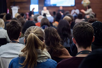 público siguiendo una conferencia en el salón de actos del museo