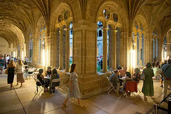 Público en el claustro del museo, sentados en mesas y sillas y andando