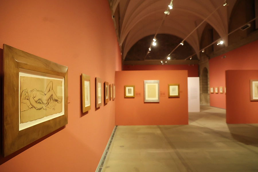 Dibujos colgados en pared caldera en una sala de la exposición. En primer plano dibujo de mujer desnuda