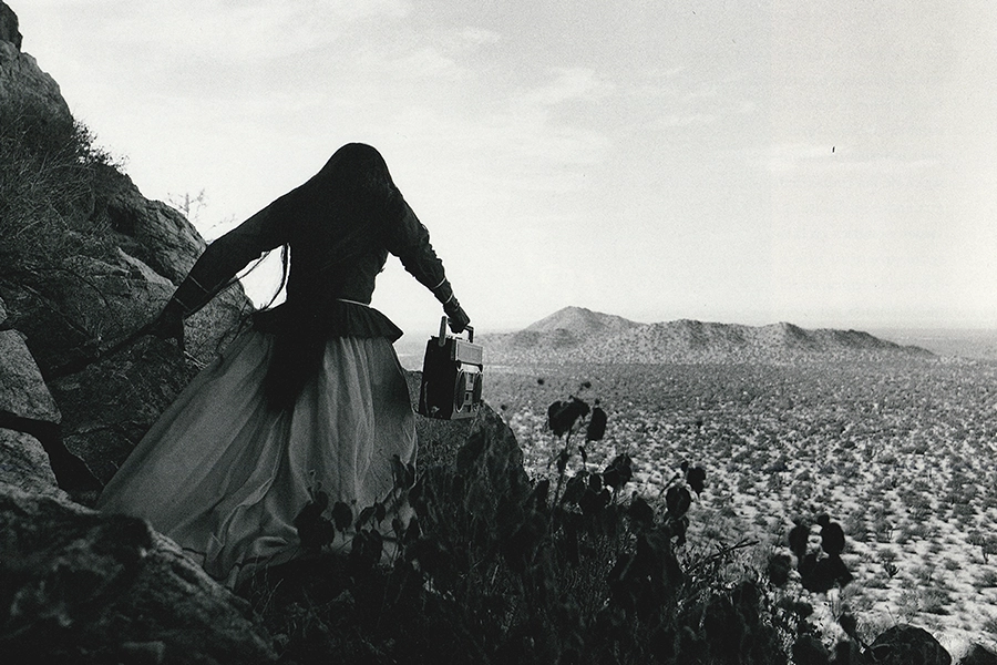 Foto en blanco y negro. A la derecha mujer de espaldas en el fondo, paisaje.