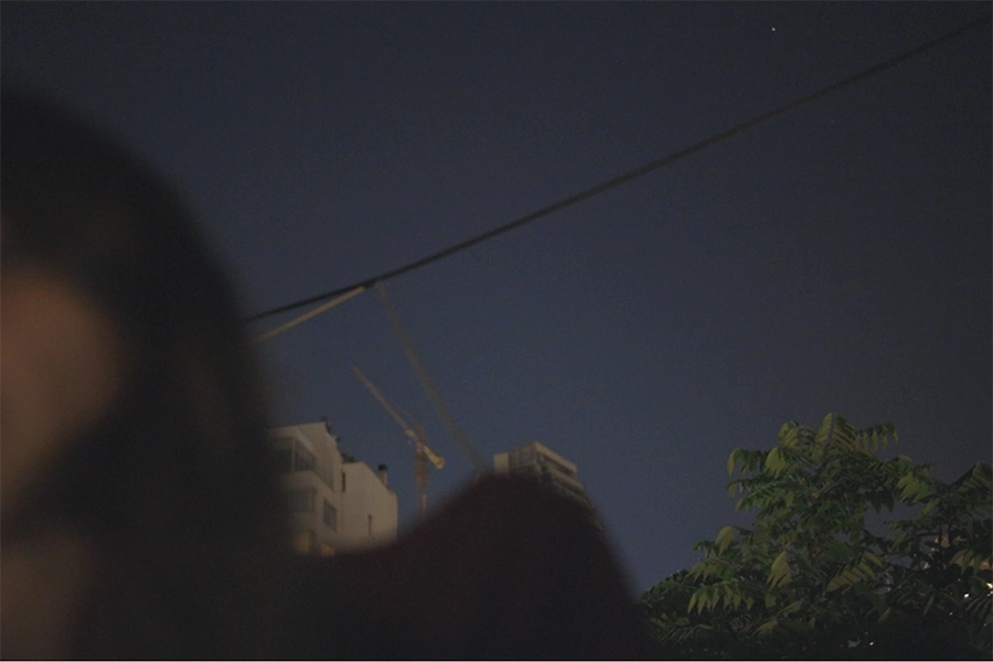 Mujer desenfocada en primer plano, al fondo el cielo de noche