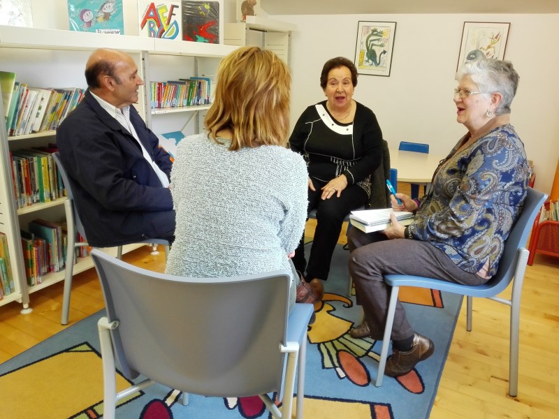 cuatro personas sentadas en la biblioteca charlando