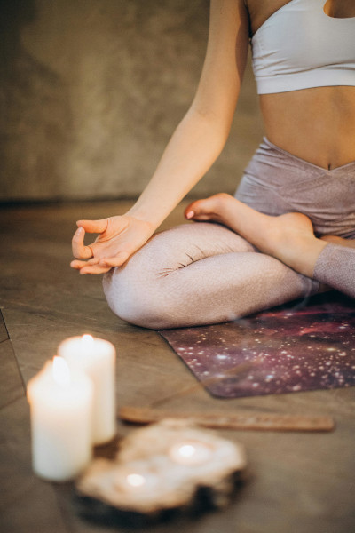 Mujer haciendo yoga junto a dos velas