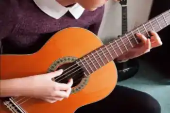 Neska baten eskuak gitarra bat jotzen