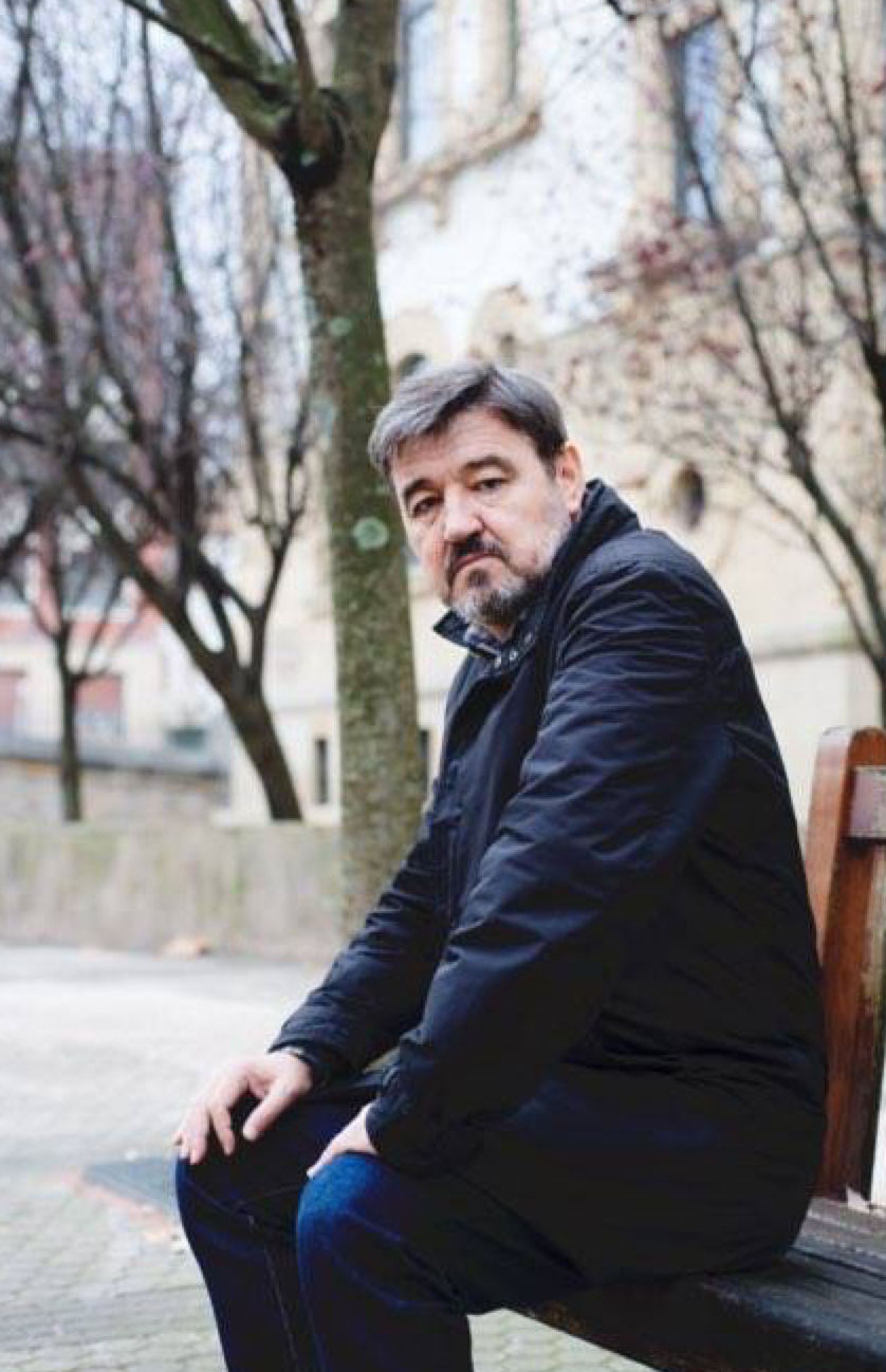 Karmelo Iribarren banku batean eserita kamarari begira