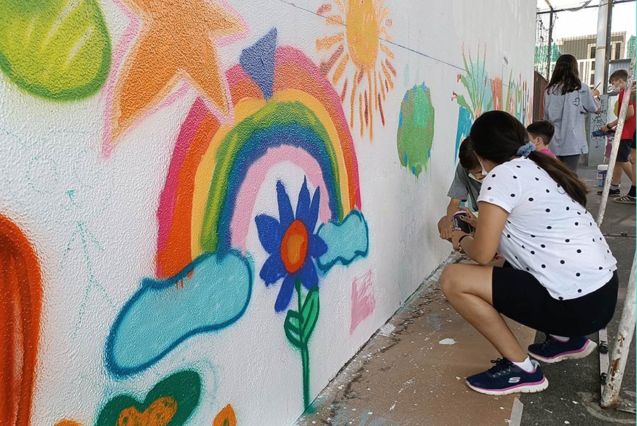 Niños y niñas y adolescentes pintando el mural