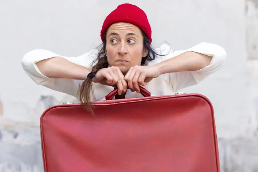 Imagen de la obra Pausa. Una chica con gorro rojo y una maleta roja en las manos