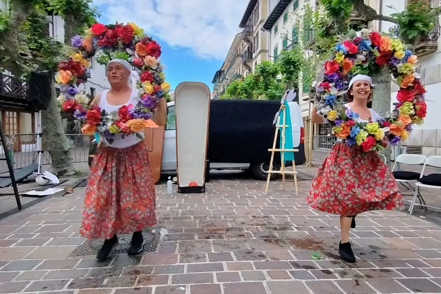 Dos personas con una corona de flores en la calle con un ataud en la mitad