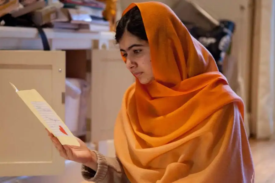 Malala Yousafzai lee vestida con un velo naranja