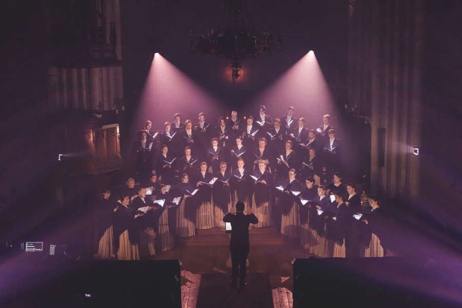 Coro actuando bajo una iluminacion rosa y morada