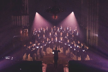 Coro actuando bajo una iluminacion rosa y morada