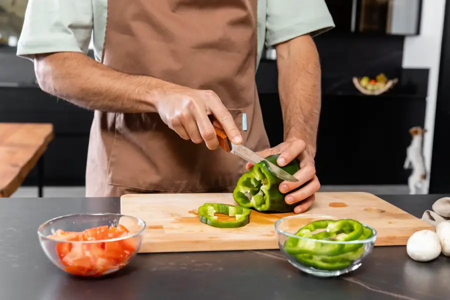 cocinero cortando un pimiento verde con un cuchillo