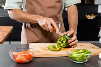 cocinero cortando un pimiento verde con un cuchillo