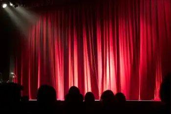 gente esperando  en un teatro con las cortinas rojas cerradas