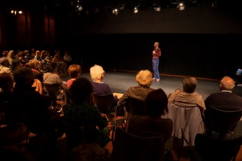 Un coreógrafo hablando frente al público en un ensayo abierto